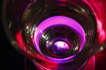 Copa de vidrio transparente con luz de superficie púrpura y rosa con borde negro desenfocado,...