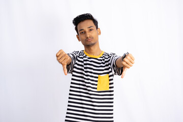 Indian man Showing Down thumbs making serious face in a white background wearing wristwatch and white tshirt