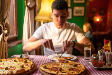 Close up of young man eating cheesy pizza, enjoying his lunch in restaurant.