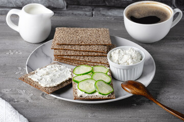 Homemade crispbread toast with cottage cheese, cucumber and coffee on a wooden table. Healthy traditional breakfast concept