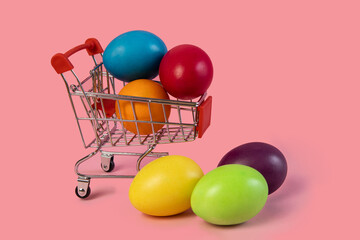 Easter postcard .Shopping cart with eggs on a pink background. The concept of a holiday, promotion, products, shopping, sale, discounts, gifts,copy space,promotions, congratulations,text, food,shop.