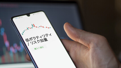 Investor analyzing an ETF. Funds stocks exchange ETFs Japanese text: Low Volatility / Risk Weighted, buy. 低ボラティリティ / リスク加重 証券取引所 投資 shares