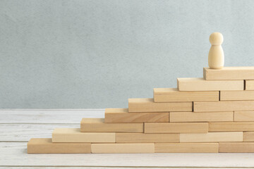 silhouette of an office worker with a suitcase climbs the stairs. gears on a wooden background.