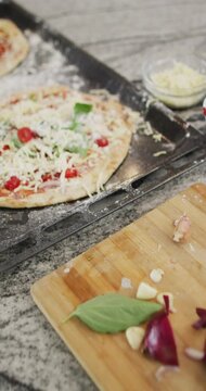 Vertical video of red onion and pizza on baking sheet in kitchen, slow motion
