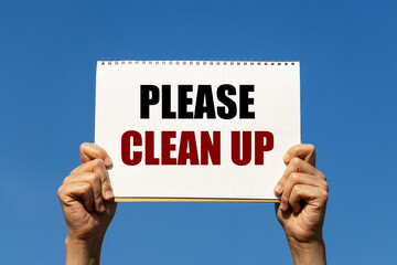 Please clean up text on notebook paper held by 2 hands with isolated blue sky background. This message can be used as business concept to inform audience to clean up place.