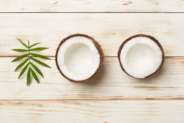 Coconut with leaves on wooden background, top view