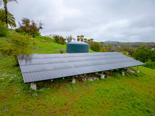 Fallbrook, California- Solar panels and cistern tank on a green mountain slope. There is a solar...