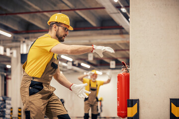 Young man using fire extinguisher in warehouse