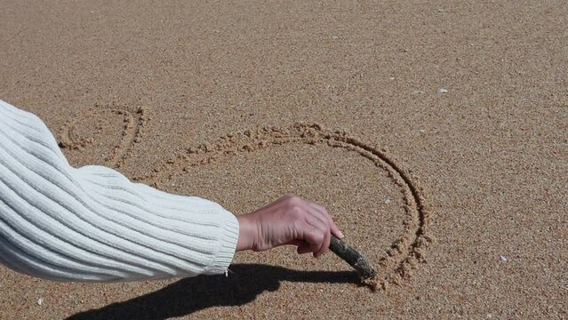 Girl drawing on  wet sand
