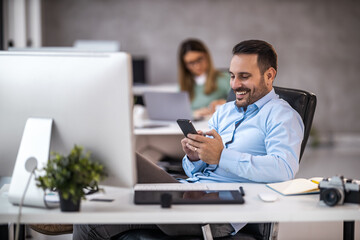 Portrait of businessman while using computer and smartphone in office