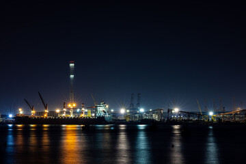 Fototapeta na wymiar shipyard dry dock maintenance and repair container ship transport and oil ship tanker, crane work and commercial port reflection in water, business and industry zone at night 