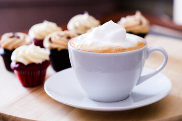 White cup of latte with mini chocolate cupcakes with peanut butter cream icing
