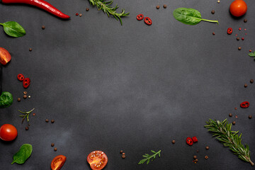 Bright frame made with fresh organic aromatic spices and herbs on black stone background with copy space for your design. Cook book cover mock up.