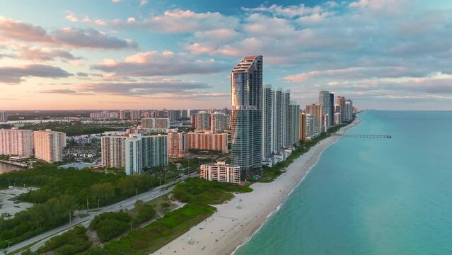 High angle view of Sunny Isles Beach city at sunset with expensive highrise hotels and condo buildings over beachfront on Atlantic shore. American tourism infrastructure in coastal southern Florida