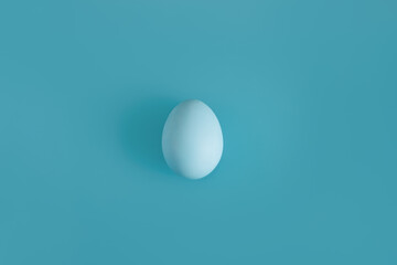 White egg on a light blue background in the center. Background concept for design, visual art, minimalism, easter.