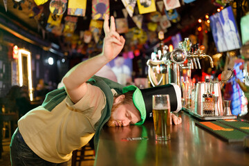 a heavily drunk ginger guy in a leprechaun hat fell asleep drunk on the counter in a pub