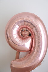 Menina de nove anos comemorando aniversário com balão inflavel rosa 
