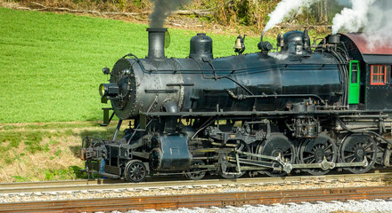 Fototapeta na wymiar A Close Side Aerial View of a Steam Engine Waiting, all Steamed Up, While it is Blowing Smoke on a Winter Day