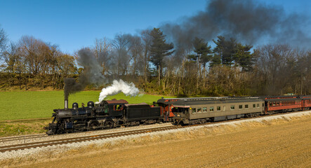 A Drone View of a Restored Steam Passenger Train Traveling Thru Farmlands Pulling Up to a Small Station and Waiting for a Second Train to Pass, on an Autumn Day