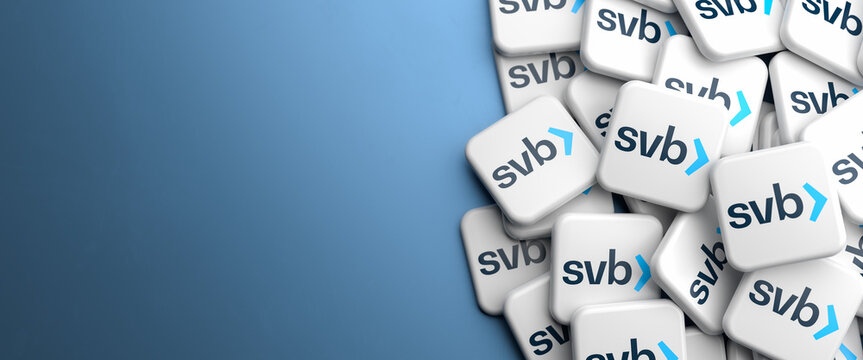Logos of Silicon Valley Bank svb on a heap on a table. Copy space. Web banner format.