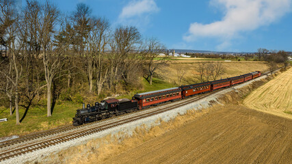 A Drone View of a Restored Steam Passenger Train Traveling Thru Farmlands of Harvested Crops on an Autumn Day