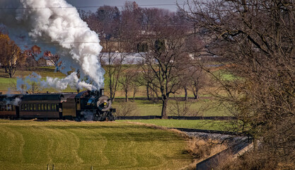 Obraz na płótnie Canvas A View of An Antique Passenger Train Approaching, Blowing Smoke and Steam, on an Autumn Day