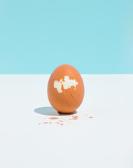Cracked boiled egg on bright sky blue and white background. Minimal healthy food concept. Easter...