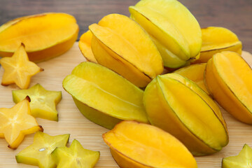 Cut and whole delicious ripe carambolas on wooden table, closeup