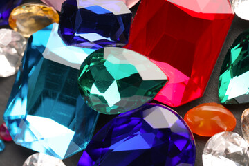 Different beautiful gemstones for jewelry on grey background, closeup