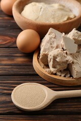 Compressed and dry granulated yeast, eggs and dough on wooden table