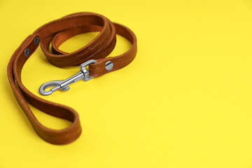 Brown leather dog leash on yellow background. Space for text