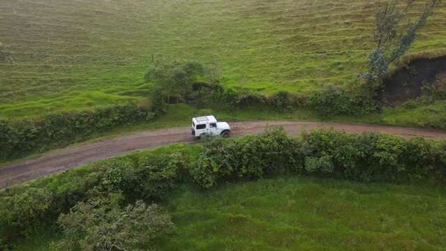 Autom&oacute;vil todoterreno viajando en carretera de terracer&iacute;a en monta&ntilde;as de Colombia, vista a&eacute;rea, dron