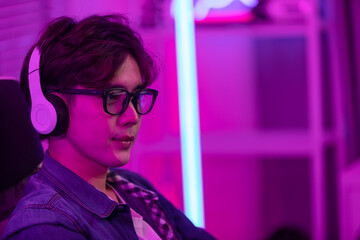 Asian gamer with a happy expression in front of a computer screen, lokking in computer screen and concentrate with online video game. Professional gamer concept © 220 Selfmade studio