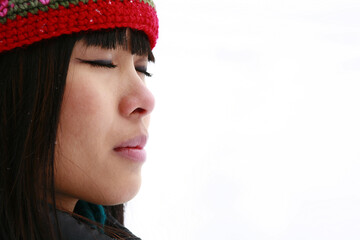 Close up portrait of young Asian woman outdoors in winter wearing wool knit tuque and scarf.