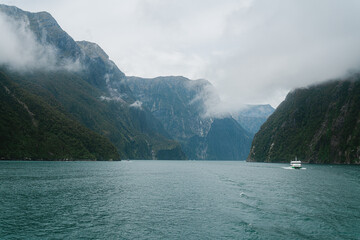 Fototapeta premium Small boat next to huge mountains, Milford Sound