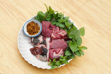 Fresh raw beef and Thai local herbal vegetables, prepare for cooking. Concept, food ingredient. Tradiotnal weird food. Popular menu in northern of Thailand.  Local food. Food ingredients to cook Larb.