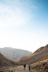 two girls on a walk in the mountains. girls with backpacks walk along a mountain path against the sky.