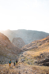 Fototapeta premium three tourists with backpacks in the mountains. Tourists travel through the rocky mountains. Active rest in mountain hiking. Adventure in the mountains.