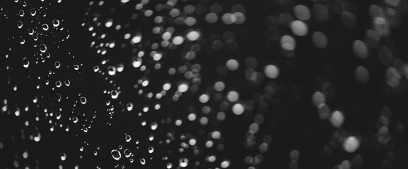 Atmospheric minimal grayscale backdrop with rain droplets on glass. Wet window with rainy drops and dirt spots closeup. Blurry minimalist monochrome background of dirty window glass with raindrops.