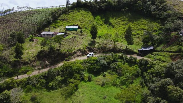 Autom&oacute;vil  peque&ntilde;o 4x4 viajando en carretera de terracer&iacute;a en monta&ntilde;as de Colombia, vista a&eacute;rea.