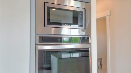 Panorama Built-in double oven and microwave on a wall with gray cabinet doors on top