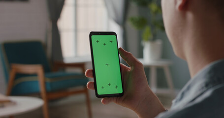 Man using a mobile phone with chroma key green screen, watching a video or having an online conference - technology, communications concept close up