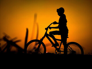 Silhouette boy riding a bicycle on the sunset