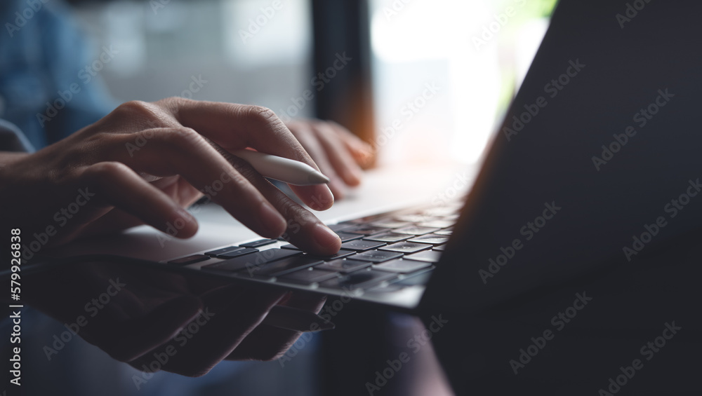 Poster Closeup of business woman hand typing and working on laptop computer, searching the information, surfing the internet with digital tablet on office table, remote work, online job concept