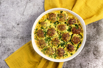 Beef and rice meatballs in cheese paprika sauce in a white baking dish on a dark grey background. Top view, flat lay