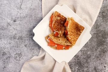Fluffy pancakes with curd cheese and cured salmon on a white square  plate on a dark background. Top view, flat lay
