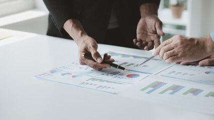 Two businessmen are brainstorming together and reviewing the company financial documents that the...