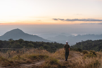 Fototapeta premium The man stand alone at top of mountain and sightseeing beautiful hill and sunrise, grain and noise for tone picture