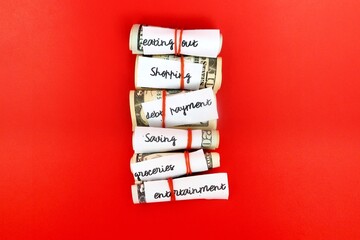 Money management saving budget plan -envelope method, small cash wrapped separately with rubber band limit for variety purposes spending- all on red background