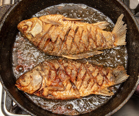 The fish is fried in oil in a frying pan.